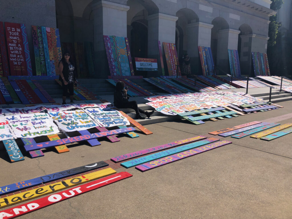 Wood Street posters laying across fence planks on stairs of capitol building in Sacramento, CA. 