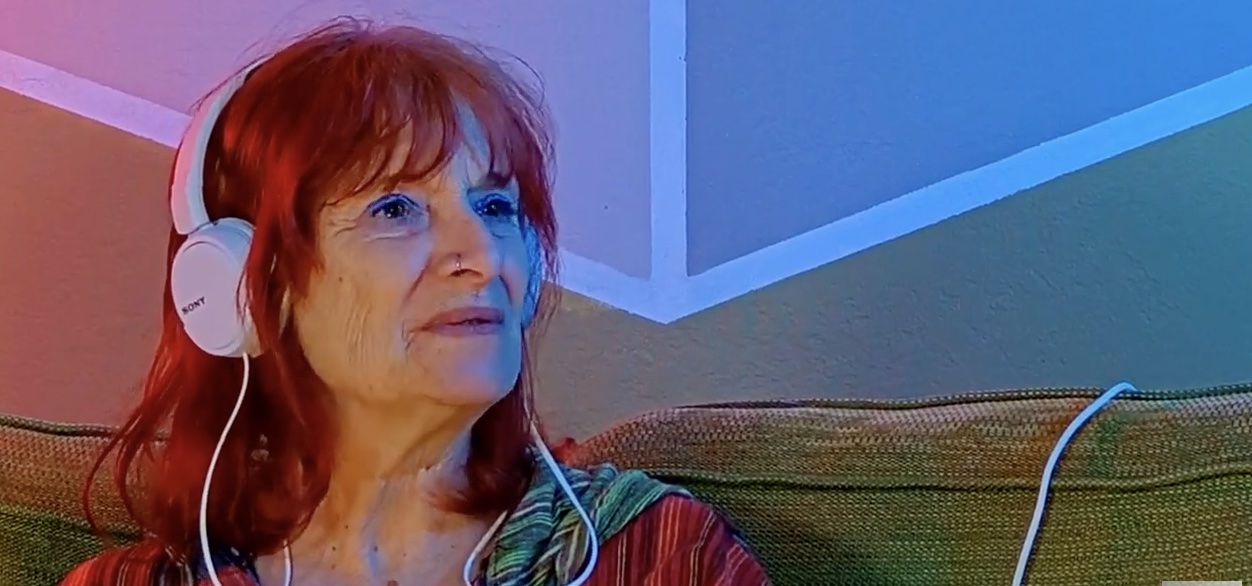 Headshot of Barbara wearing earphones, talking during podcast.