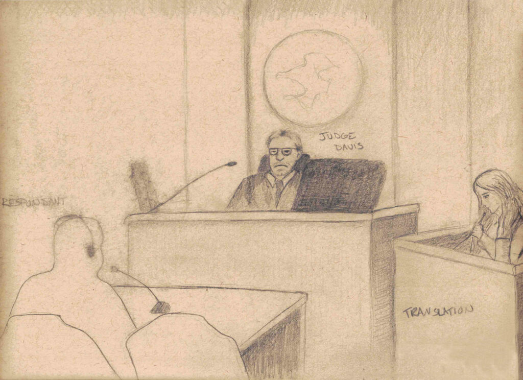 pencil drawing of court room with unhappy judge in the center sitting at raised desk with a court seal behind his head. Translator is seated at lower tesk at right. Silhouette of a respondant is seated lowest, in lower left hand corner. 